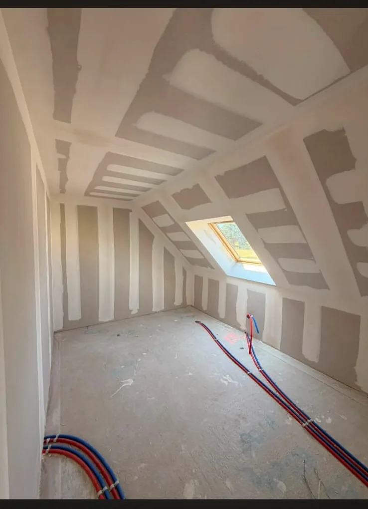 Rampants et plafond plaqués sous une fenêtre de toit, bandes de finition posées